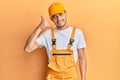 Hispanic young man wearing handyman uniform smiling doing phone gesture with hand and fingers like talking on the telephone Royalty Free Stock Photo