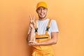 Hispanic young man wearing handyman uniform smiling with happy face winking at the camera doing victory sign with fingers Royalty Free Stock Photo