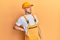 Hispanic young man wearing handyman uniform suffering of backache, touching back with hand, muscular pain Royalty Free Stock Photo