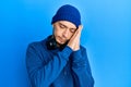 Hispanic young man wearing sweatshirt and headphones sleeping tired dreaming and posing with hands together while smiling with Royalty Free Stock Photo