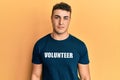 Hispanic young man wearing volunteer t shirt relaxed with serious expression on face