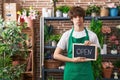 Hispanic young man working at florist holding open sign depressed and worry for distress, crying angry and afraid