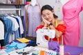 Hispanic young woman dressmaker designer using sewing machine sleeping tired dreaming and posing with hands together while smiling Royalty Free Stock Photo