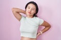 Hispanic young woman standing over pink background suffering of neck ache injury, touching neck with hand, muscular pain Royalty Free Stock Photo