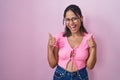 Hispanic young woman standing over pink background wearing glasses success sign doing positive gesture with hand, thumbs up Royalty Free Stock Photo