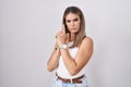 Hispanic young woman standing over white background holding symbolic gun with hand gesture, playing killing shooting weapons,