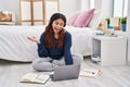 Hispanic young woman using laptop sitting on the floor at the bedroom celebrating achievement with happy smile and winner Royalty Free Stock Photo