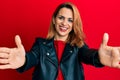 Hispanic young woman wearing black leather jacket looking at the camera smiling with open arms for hug Royalty Free Stock Photo