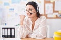 Hispanic young woman working at the office wearing headset and glasses pointing thumb up to the side smiling happy with open mouth Royalty Free Stock Photo