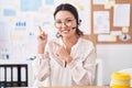 Hispanic young woman working at the office wearing headset and glasses smiling and looking at the camera pointing with two hands Royalty Free Stock Photo