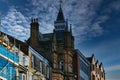 Historic architecture with a spire against a dramatic sky, flanked by modern buildings and scaffolding in Harrogate, England