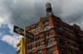 Historic brick building in New York City with water tower on top, stoplight in foreground