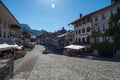 Cobbled square with fountain and old houses decorated with flowers in summer in Gruyeres, Switzerland.