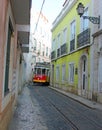 Historic electric tramway no. 28 between narrow houses in lisbon, portugal