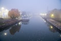 Historic Erie Canal in Fairport village with barge cruise boat tour, foggy morning mist and reflection of colorful fall foliage Royalty Free Stock Photo