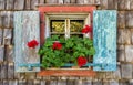 Historic farmhouse window with red geraniums.