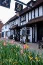Historic half timbered Tudor pub called the Queen`s Head, in Pinner High Street, Pinner, Middlesex UK. Tulips in foreground.