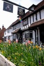 Historic half timbered Tudor pub called the Queen`s Head, in Pinner High Street, Pinner, Middlesex UK. Tulips in foreground.