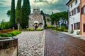 Historic italian church in Gorizia castle district on rainy day with pines in background and well Royalty Free Stock Photo