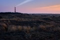 Historic lighthouse of Hollum with light beam, Ameland with a red and orange sky during sunset, sunrise. Dark dunes with Royalty Free Stock Photo