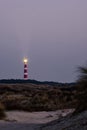 Historic lighthouse of Hollum with light beam, Ameland with a red and orange sky during sunset, sunrise. Dark dunes with Royalty Free Stock Photo