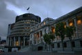Modern expansion of conic Beehive in gray concrete to old Edwardian parliament illuminated at dusk, Wellington, New Zealand