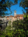 Ponte del Diavolo and Bell tower of Cividale del Friuli, Italy. Shot through branches on south shore on sunny day