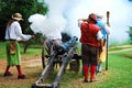 Historic re-enactors cover their ears during a cannon firing demonstration