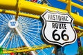 Historic Route 66 marker. West roller coaster and Ferris Wheel in amusement Pacific Park on famous Santa Monica Pier. - Santa