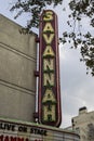 The Historic Savannah Theatre with a tall red neon sign with lush green trees and blue sky in Savannah Georgia