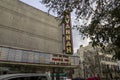 The Historic Savannah Theatre with a tall red neon sign with lush green trees, tall black light posts, cars parked