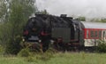 Historic steam locomotive with passenger wagons on rail tracks