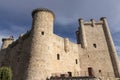 A historic stone castle with tall towers and crenellated parapets, under a blue sky with wispy clouds Royalty Free Stock Photo