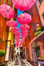 Historic tenement houses and narrow streets decorated with pink umbrellas of old town in perfumery city of Grasse in France