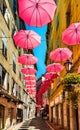 Historic tenement houses and narrow streets decorated with pink umbrellas of old town in perfumery city of Grasse in France