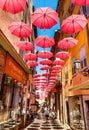 Historic tenement houses and narrow streets decorated with pink umbrellas of old town of perfumery city of Grasse in France