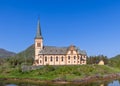 Historic Vagan Kirke and spire reflect in water, surrounded by Lofoten\'s hills