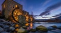 Historic Waterwheel Structure Illuminated Alongside Calm River During Twilight Hours Royalty Free Stock Photo
