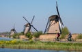 Historic windmills with cyclists cycling along the side of the canal in the foreground, at Kinderdijk, Holland