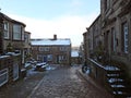 Main street of the yorkshire village of heptonstall in winter with snow covered roofs and street