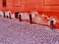 Historical dark stone bollards near red facade house and granite cubes paving street