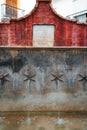 A historical fountain in Ojen, Spain, with red walls and star-shaped water spouts, evoking the town's heritage