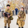 Historical reconstruction of the Second World War. A soldier walks with the nurse along the embankment and plays the accordion