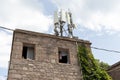 historical stone house, radio base station apparatus on it. against the sky.