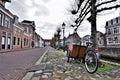 historical street with old houses and cargo bike parked against a tree soft pastel winter colors