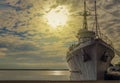 Historical warship standing in the port against the backdrop of the rising sun in Gdynia Royalty Free Stock Photo