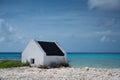 Historical white slave house on a beach under a cloudy sky in Bonaire