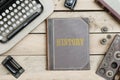 History on old book cover at office desk with vintage items Royalty Free Stock Photo