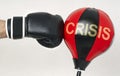 Hit the crisis concept with a strong man`s hand in a boxing glove hits the punching bag with text Crisis
