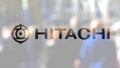 Hitachi logo on a glass against blurred crowd on the steet. Editorial 3D rendering